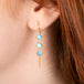 Gold earrings featuring a trio of golden hills turquoise stones, worn on a person's ear.