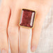 A close up of a person wearing a handcrafted ring with a tourmaline gemstone, 18k gold bezel and sterling silver band