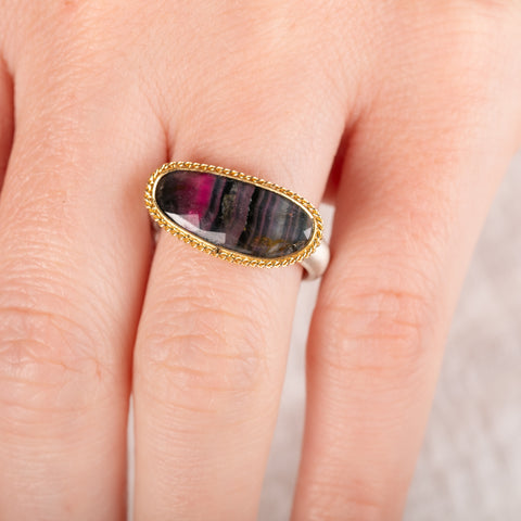 Close up of hand wearing a watermelon tourmaline ring with gold bezel and silver band