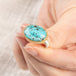 A close up of a person holding a handmade fine jewelry turquoise ring with an 18k gold bezel and sterling silver band