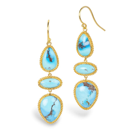 A pair of gold drop earrings featuring three stacked turquoise stones in various shapes, set in twisted gold bezel settings, shown on a white background.