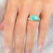 An oval ring featuring a green variscite stone with a natural matrix, set in a gold bezel with a sterling silver band worn on a finger