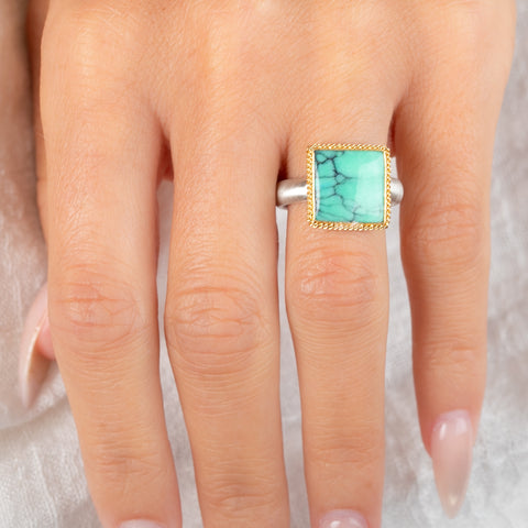 Gold and silver ring featuring a green Variscite stone worn on a finger