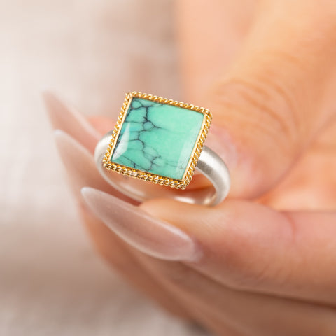 Gold and silver ring featuring a green Variscite stone held in a hang