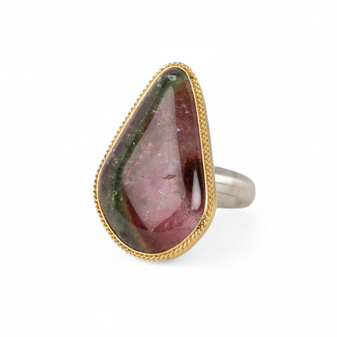 Ring with a teardrop-shaped watermelon tourmaline gemstone in a gold bezel with a sterling silver band on a white background