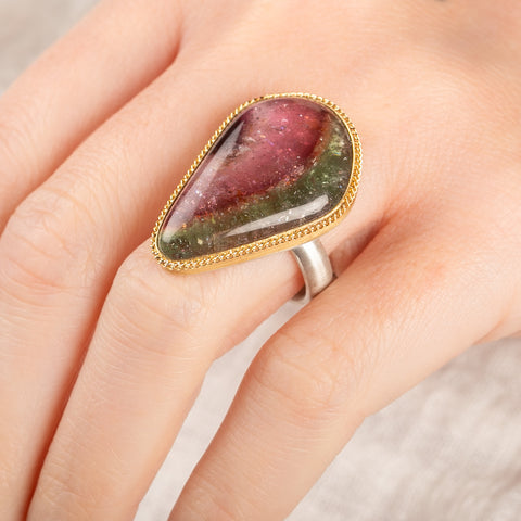 Ring with a teardrop-shaped watermelon tourmaline gemstone in a gold bezel with a sterling silver band