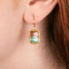 Gold earrings featuring watermelon tourmaline gemstones in duo-tones, shown worn on a person's ear.