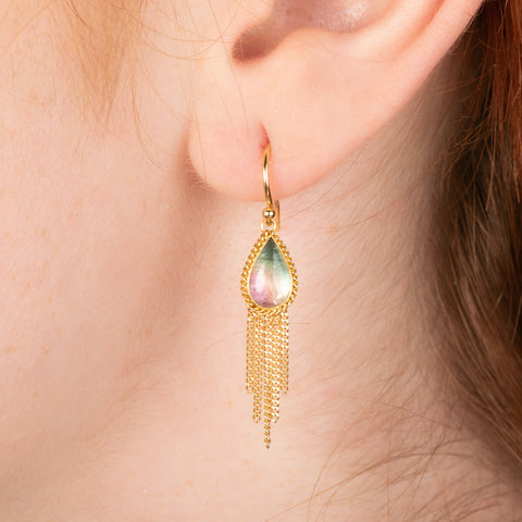 Gold earrings featuring watermelon tourmaline earrings, shown worn in a person's ear.