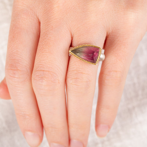 Hand wearing a watermelon tourmaline ring with gold bezel and silver band