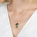 Gold mushroom necklace with a colorful boulder opal pendant on a person wearing a white top.