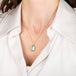 Gold necklace with an aquamarine gemstone pendant on a person