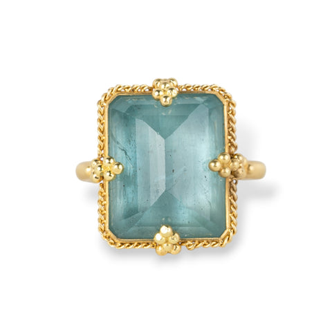 Gold ring with a rectangular aquamarine gemstone on a white background
