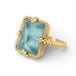 Gold ring with a rectangular aquamarine gemstone on a white background