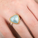 Heart-shaped ring with aquamarine stone, gold bezel and silver band on a hand