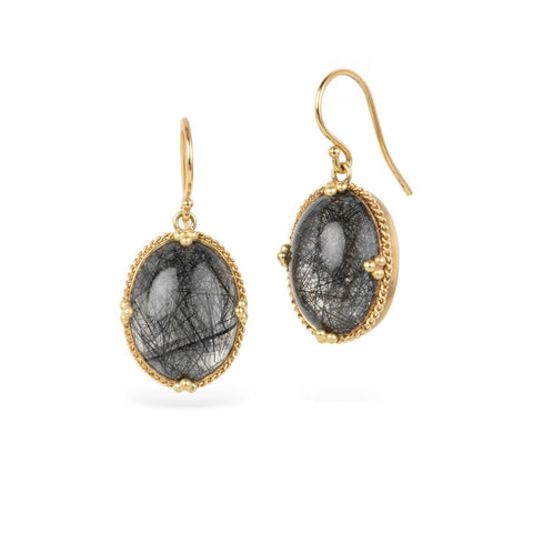 Gold earrings featuring toumalated quartz on a white background