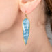 Blue aquamarine teardrop earring with gold frame worn by a person