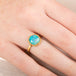 Gold ring with an Ethiopian opal stone on a person's finger