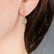 Gold earrings with boulder opal stones and chain fringes worn on a person