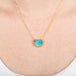 Necklace with a heart-shaped boulder opal stone pendant on a gold chain against a person