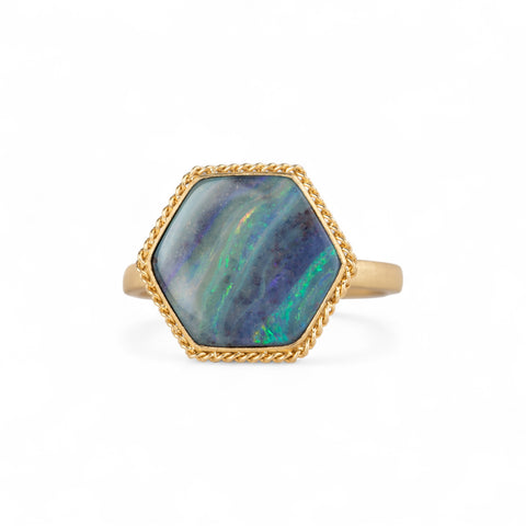 Gold ring with a hexagonal boulder opal stone on a white background