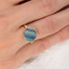Gold ring with a hexagonal boulder opal stone on a person's finger