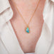 Boulder opal pendant necklace with a gold setting worn on a person
