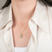 A gold necklace featuring a boulder opal gemstone worn on a person