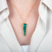 Triangle-shaped boulder opal stone pendant with a gold setting on a person