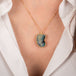 Gold necklace featuring a boulder opal carved into a wing on a person's neck