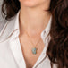 Gold necklace featuring a carved boulder opal stone on a person's neck