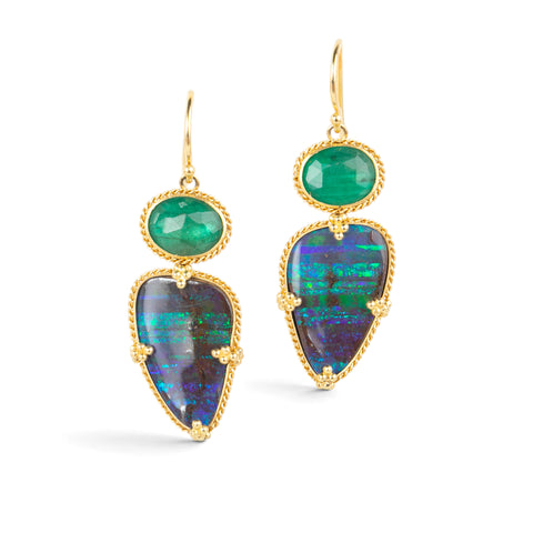 Gold earrings featuring boulder opals and emeralds against a white backdrop