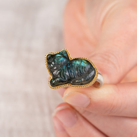 Hand holding a labradorite cat ring with an 18k gold bezel and sterling silver band