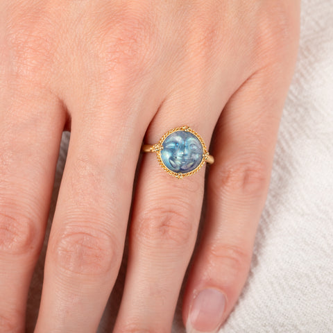 Gold ring with a carved moonstone on a person's finger