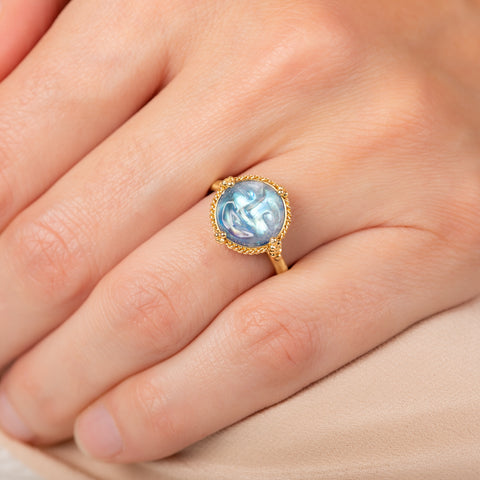 Gold ring with a carved moonstone on a person's finger