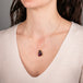 Gold necklace featuring a carved tourmaline parrot pendant on a person's neck