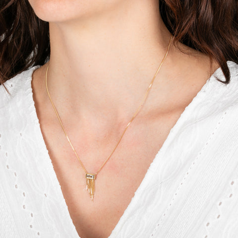 Gold necklace with a rectangular diamond and gold fringe on a person