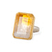 Ring with a bicolor citrine stone, gold setting and silver band on a white background