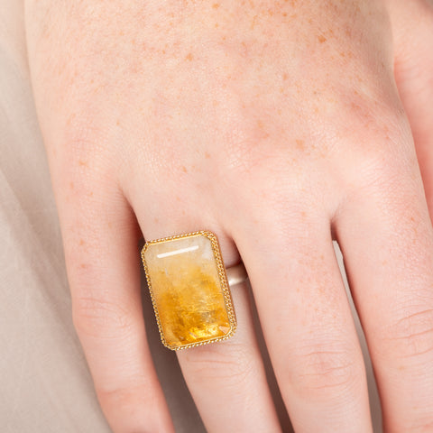 Ring with a large citrine stone, gold setting and silver band on a person's hand
