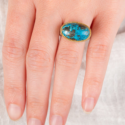 Hand wearing a turquoise fine jewelry ring with 18k gold bezel and sterling silver band