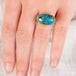 Hand wearing a turquoise fine jewelry ring with 18k gold bezel and sterling silver band