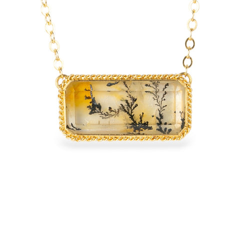 Gold necklace with a rectangular pendant featuring a dendritic quartz with a nature design on a white background