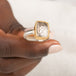A gold and silver ring featuring a dendritic quartz stone with a detailed tree branch pattern inside, held in hand