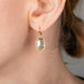Gold earring with a diamond worn by a person