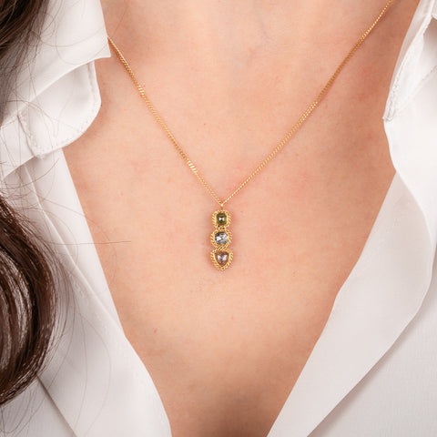 Gold necklace with a pendant featuring three different colored Diamonds on a person