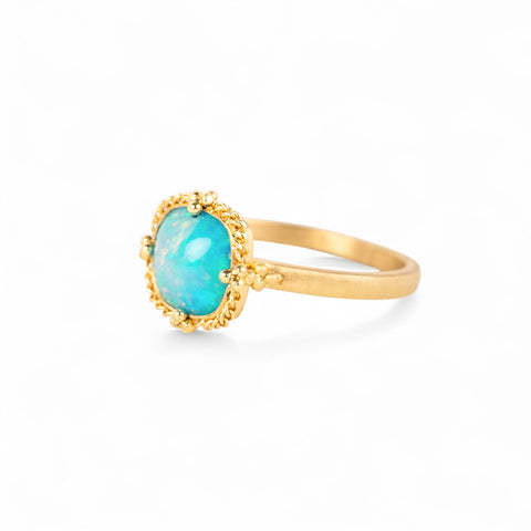 Gold ring with an Ethiopian opal stone on a white background