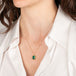 Gold necklace featuring an emerald gemstone on a person