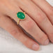 Gold ring with an emerald gemstone on a person's finger