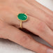 Gold ring with an emerald gemstone on a person's finger