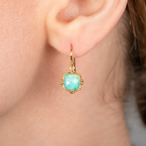 Gold earring with an Ethiopian opal gemstone worn by a person