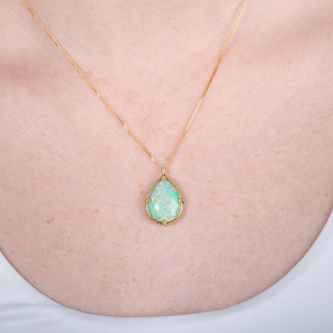 Ethiopian opal teardrop pendant necklace with gold setting on a person